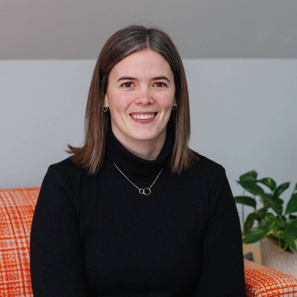 Person sitting with a plant nearby.